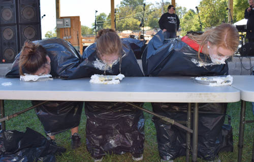 Contestants bury their faces in pie for the banana pie eating contest.